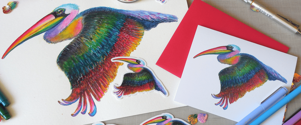 Hand-drawn rainbow pelican illustration with stickers and colorful envelope on a desk.