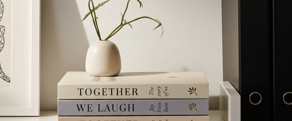 Neutral decorative book set styled on a modern white coffee table with friends enjoying coffee 