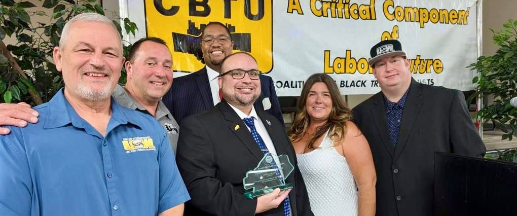 a group of people standing around a man in a suit and tie