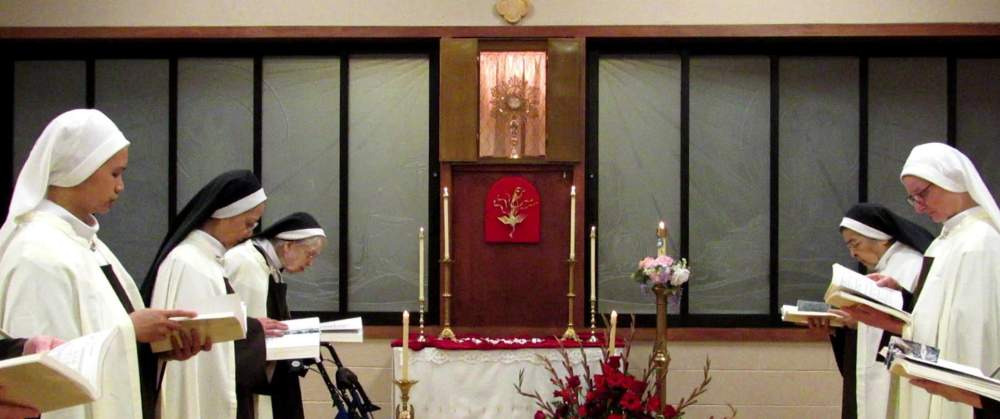 Nuns praying in the choir with the Blessed Sacrament exposed.