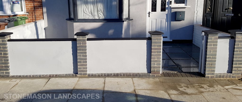 Blue perfurated brick wall with black coping and caps and grey rendering
