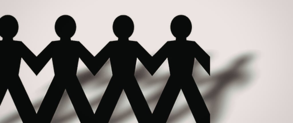 Black paper chain people holding hands representing community teamwork and unity.