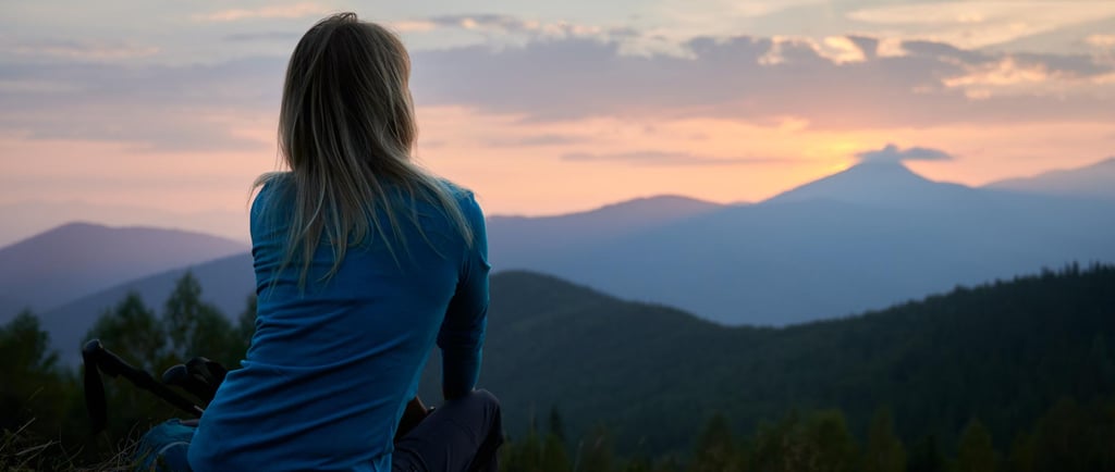 Solo female traveler overlooking the mountains during sunset