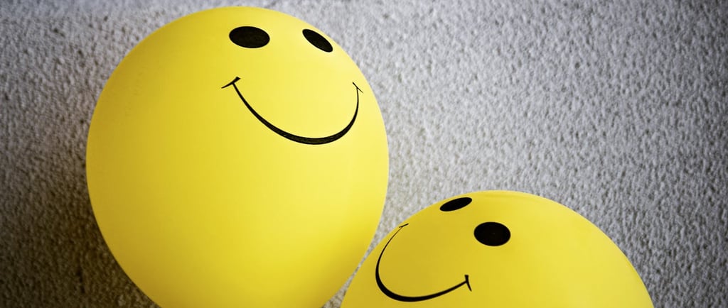 three yellow balloons with smiley faces on them
