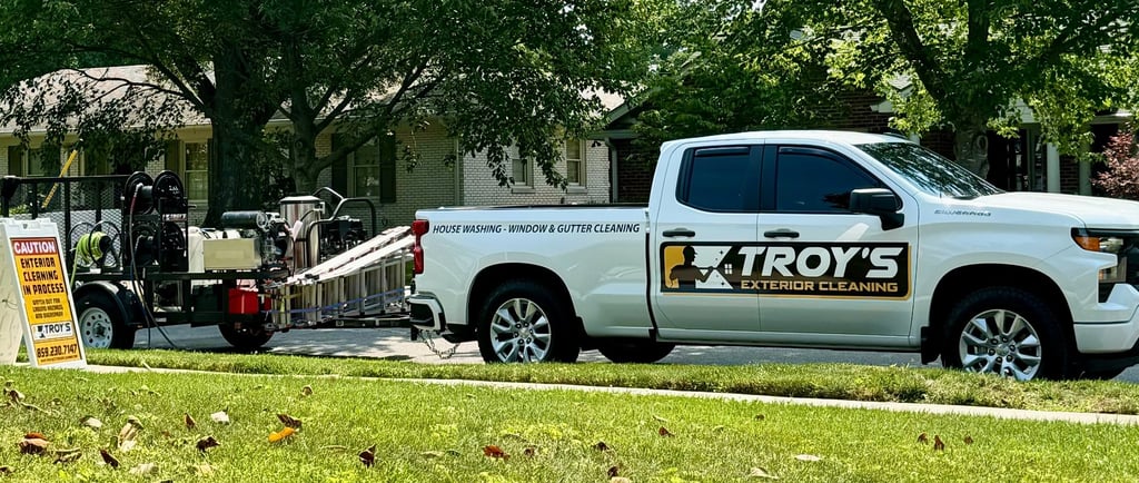 White truck with Troys Exterior cleaning logo and pressure washing trailer in tow