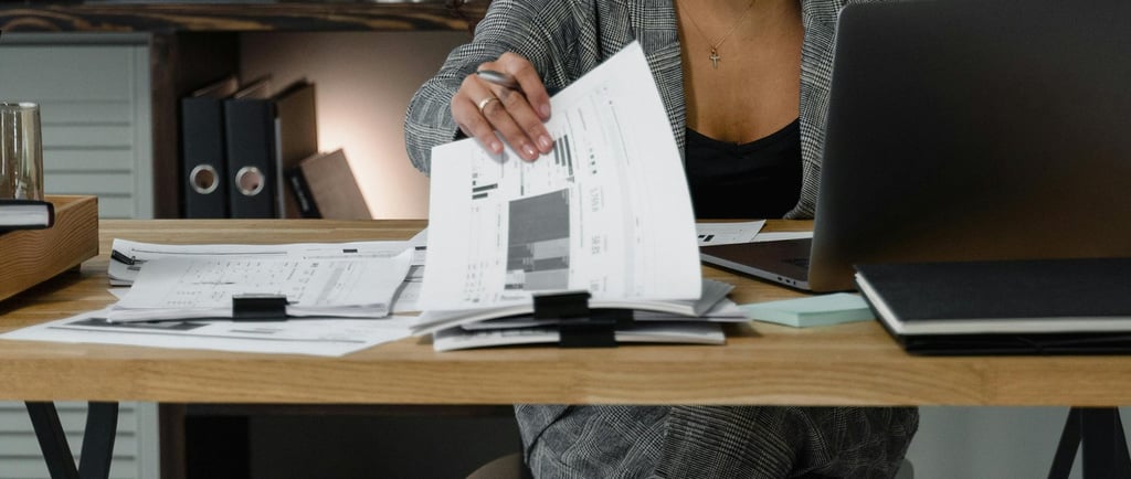Frau sitzt besorgt am Tisch und betrachtet Papiere.