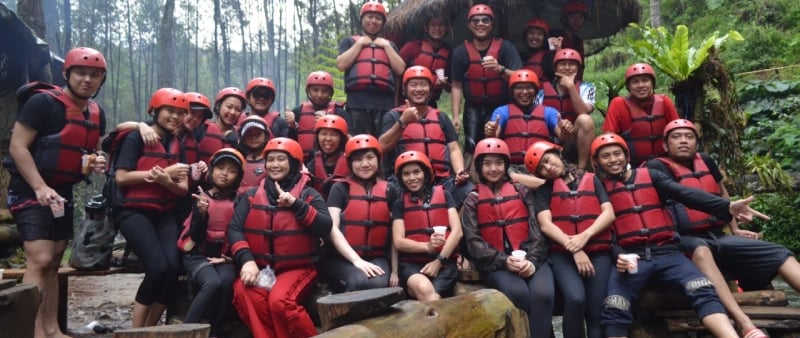 Foto karyawan perusahaan saat gathering atau team building outdoor, mengenakan alat keselamatan arung jeram di tengah hutan p