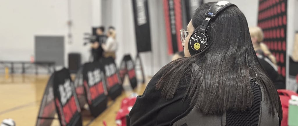 a woman in a black jacket and headphones on a basketball court