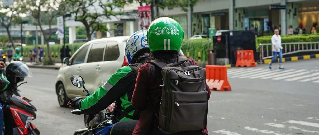 A Grab motorbike rider carrying a passenger on a city street in Vietnam