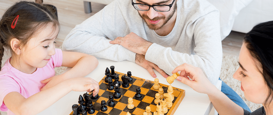 Parent playing chess with their kids