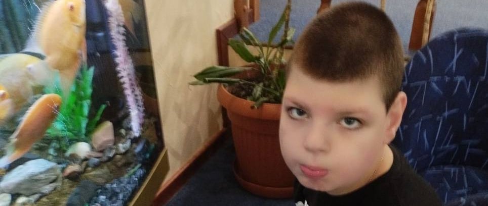 молодий хлопчик сидить у кріслі з акваріумом