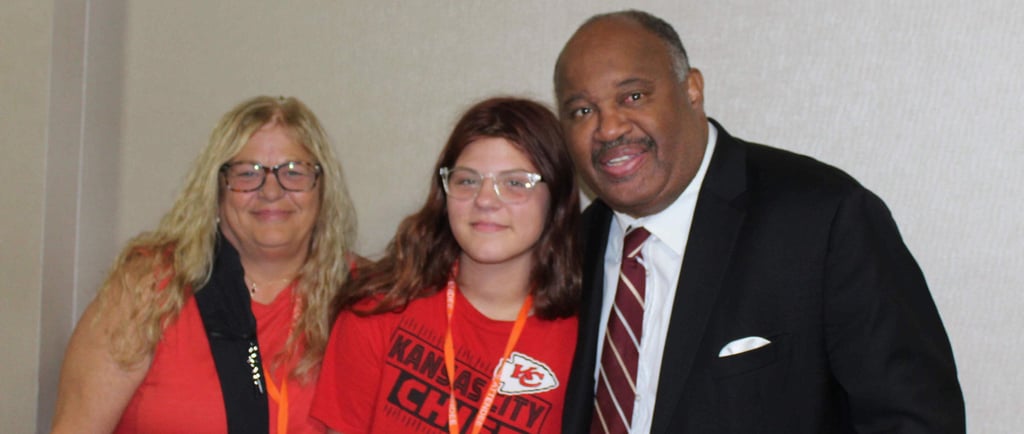 Dominic Carter at the Missouri Kinship Conference speaking with a teenager and her aunt who is raising her — highlighting fam