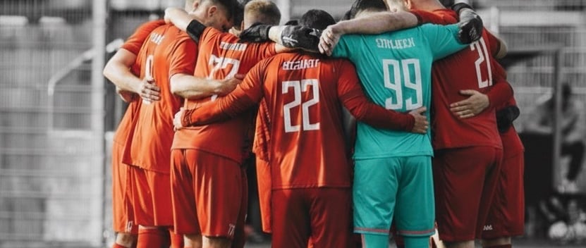 a group of soccer players huddle around a soccer field