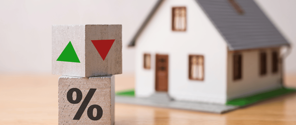blocks with green and red arrows for interest rates beside tiny house