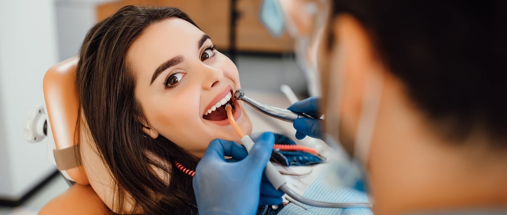 a woman is sitting in a chair and is having her teeth brushed