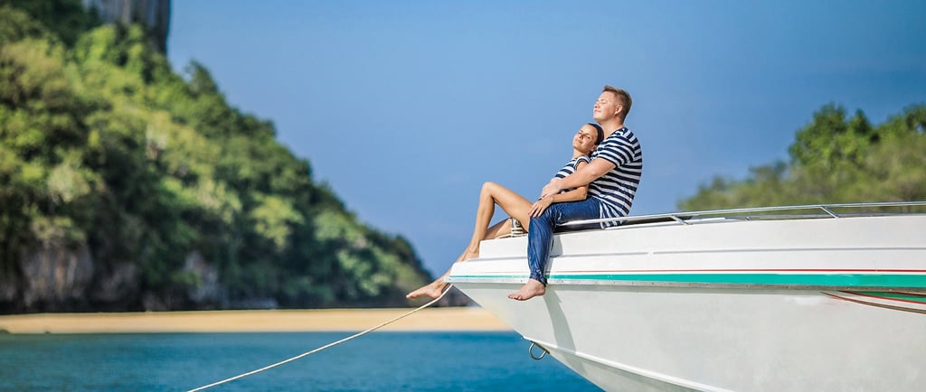 A couple sitting at the edge of a white speedboat, enjoying the sun during their honeymoon on Samui