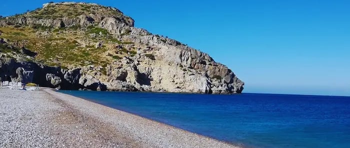 a beach with a rocky beach and a blue sky
