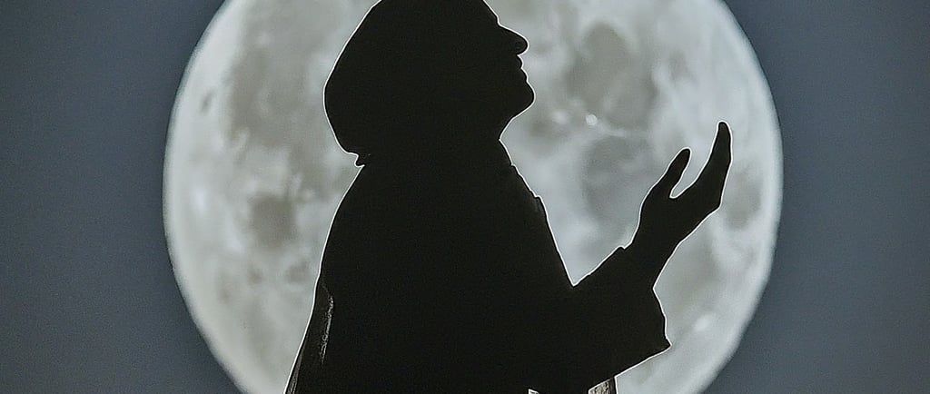 a person praying in front of a full moon