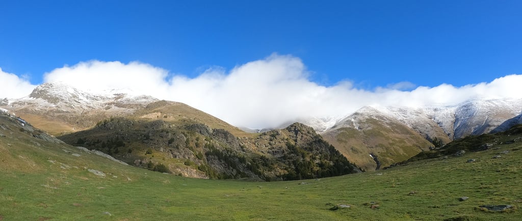 View of Mount Puigmal with green slopes in the foreground and snow-covered peaks in the background i