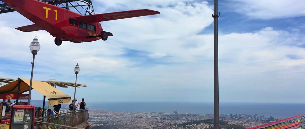 a red plane flying over Barcelona city in Tibidabo amusement park