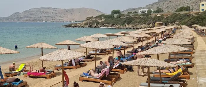 a beach with many people sitting on lounge chairs
