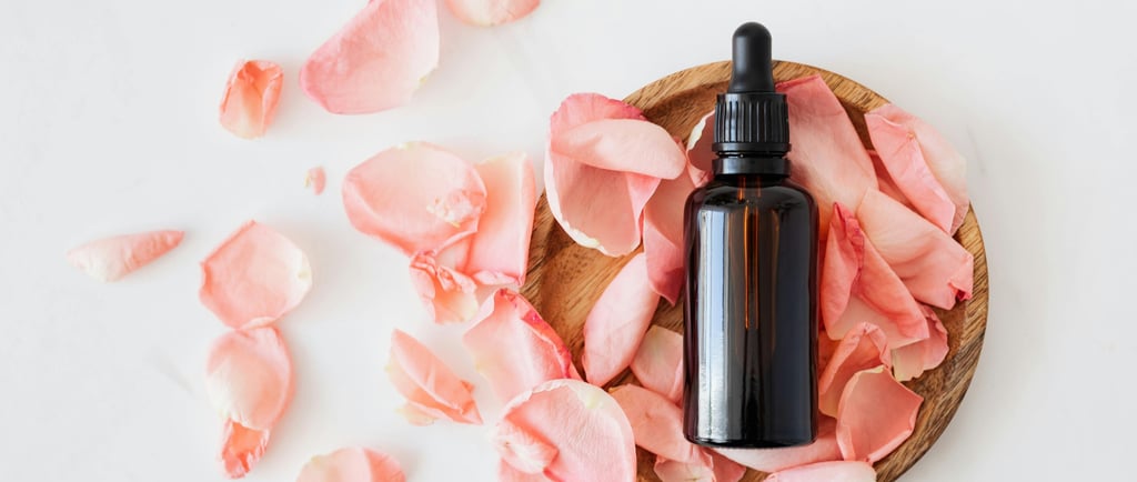 a bottle of essential oils with pink flower petals