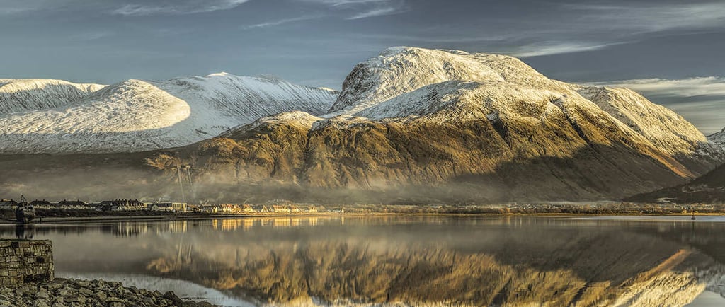 Winter view of Ben Nevis mountain range from the base with mist rising over the peaks in Scotland