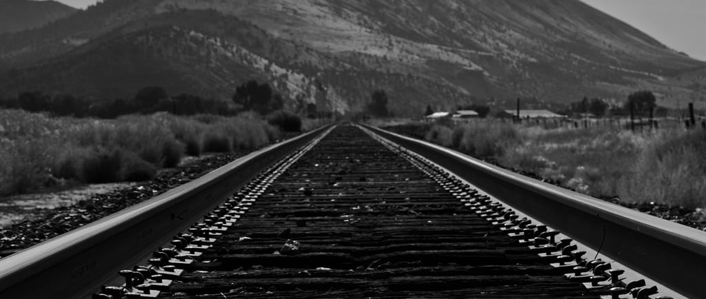 a train track with a mountain in the background taken by Jordan Boyle of JJ Everitt Photography