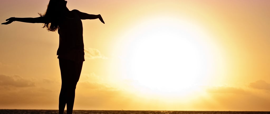 a woman standing on a dock with her arms outstretched out to the water
