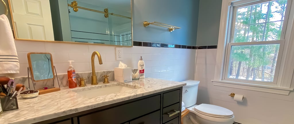 Bathroom vanity and white stone countertop with brass accesories