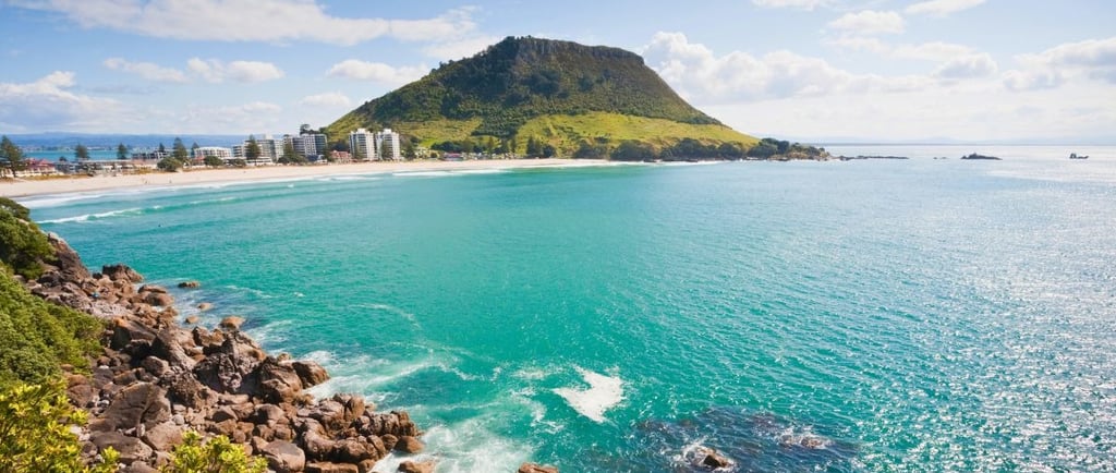 Vista do monte e do mar da Bay of Plenty em Tauranga, com a cidade ao fundo e céu claro.