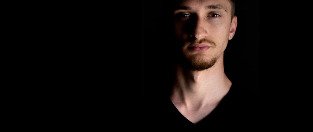 Close-up shot of music artist Valah's face in the dark, illuminated by dramatic lighting.