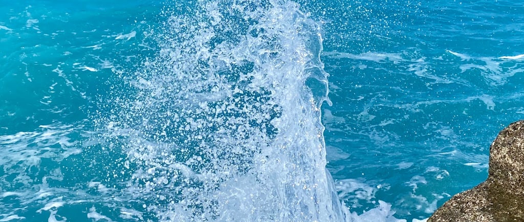 a wave crashing into the ocean on a sunny day