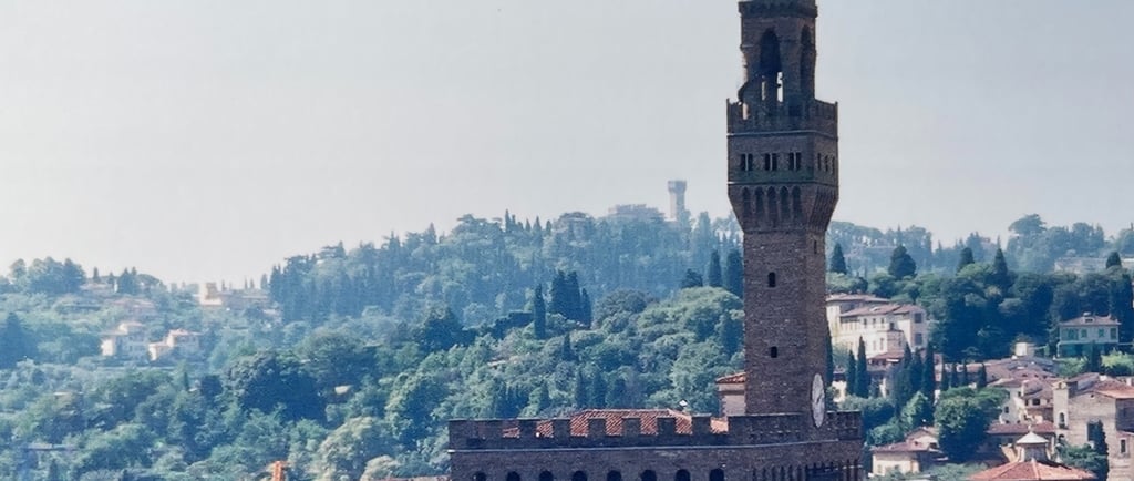 the palazzo vecchio in Florence, Italy, surrounded by other buildings and Tuscan countryside behind