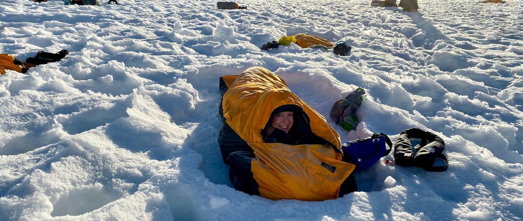 a person laying on the snow in a warm sleeping bag