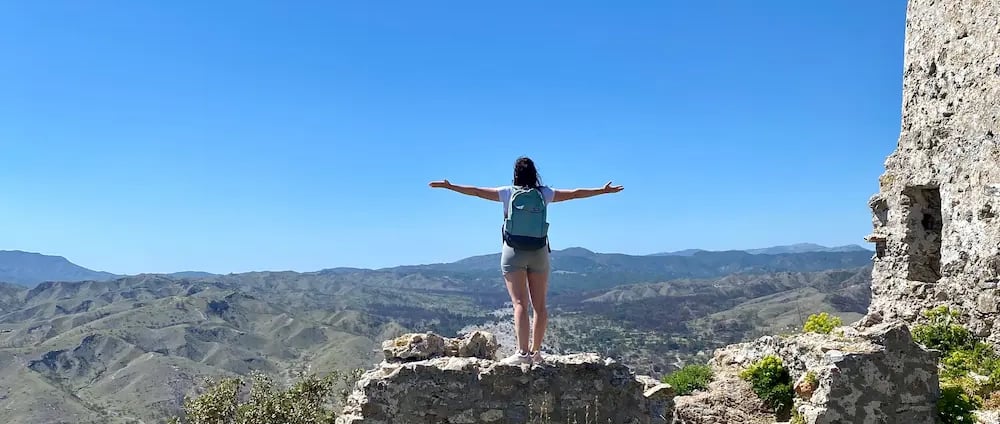 a woman standing on a rock formation with her arms outstretched out