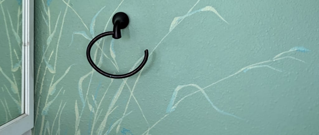 Small bathroom wall accent painting of tall bending dune grasses using cream colors, blues, and greens.