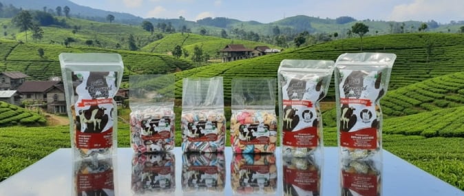 Berbagai varian permen susu karamel khas oleh oleh pangalengan dengan latar belakang pemandangan kebun teh hijau yang asri