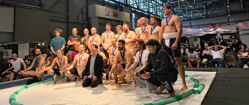 21 hommes et femmes prenant la pose sur un dohyo de Sumo
