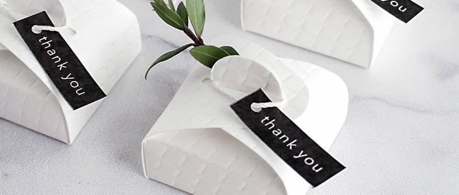 a table with a bunch of small white paper wedding favour boxes