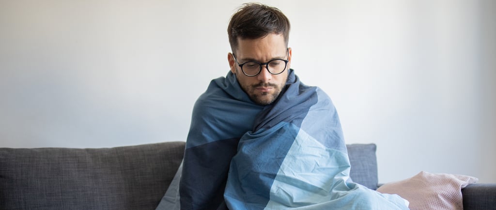 a man sitting on a couch with a blanket on it