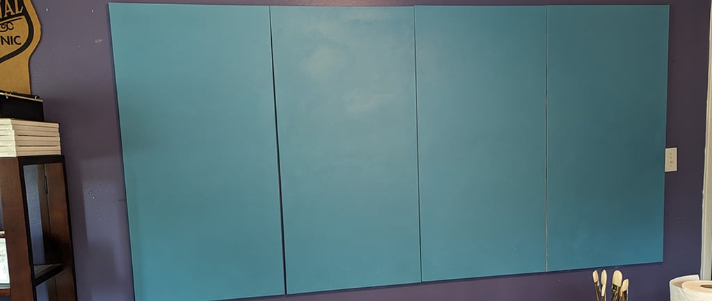 Four stretched canvas panels painted a seashore blue.