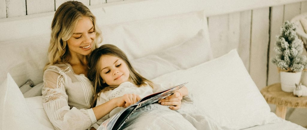 a woman and her daughter reading a book in bed and learning reading