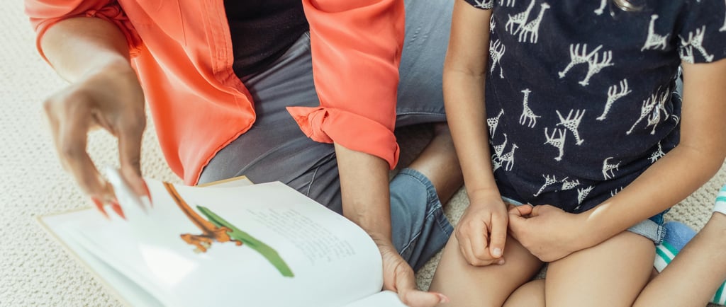 a woman and chil sitting on the floor reading a book