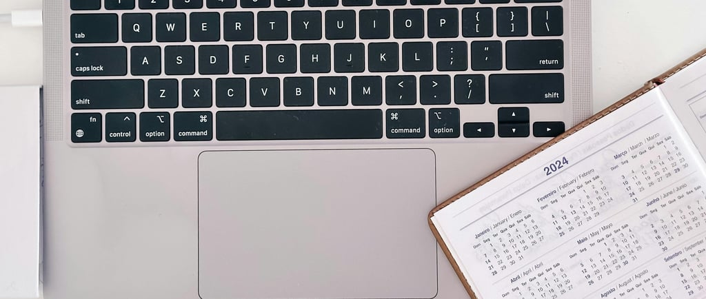 An open calendar planner, slightly laid over the keyboard of an open laptop.