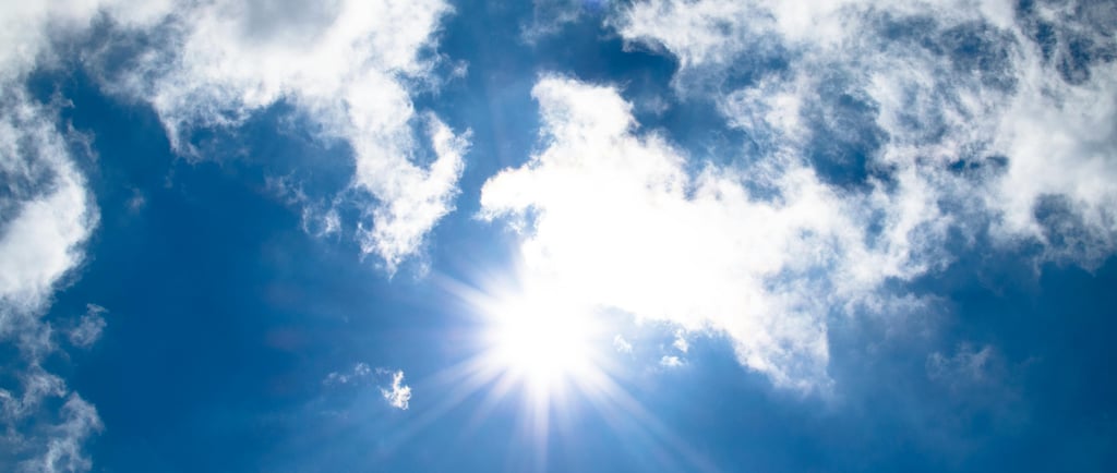 a plane flying through the sky with a sun shining through the clouds