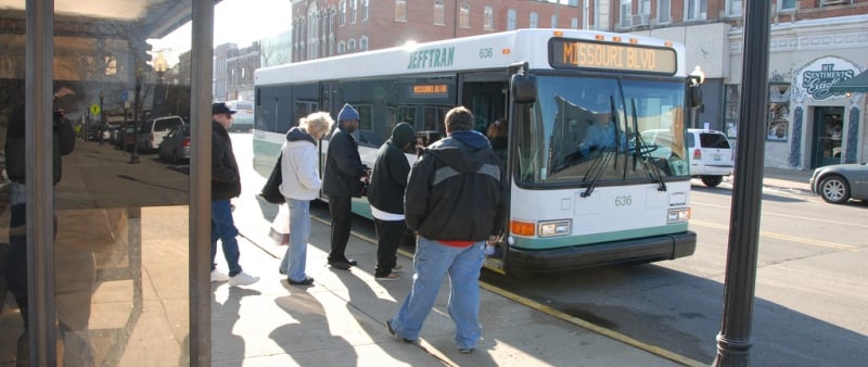 A group of people at a bus stop boarding a Jefferson City bus