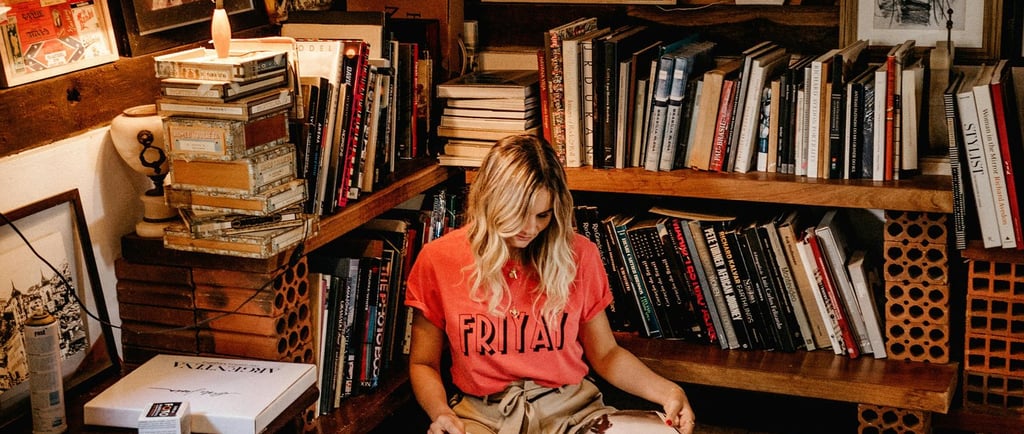 Young woman in attic, with bookshelves, reading a book