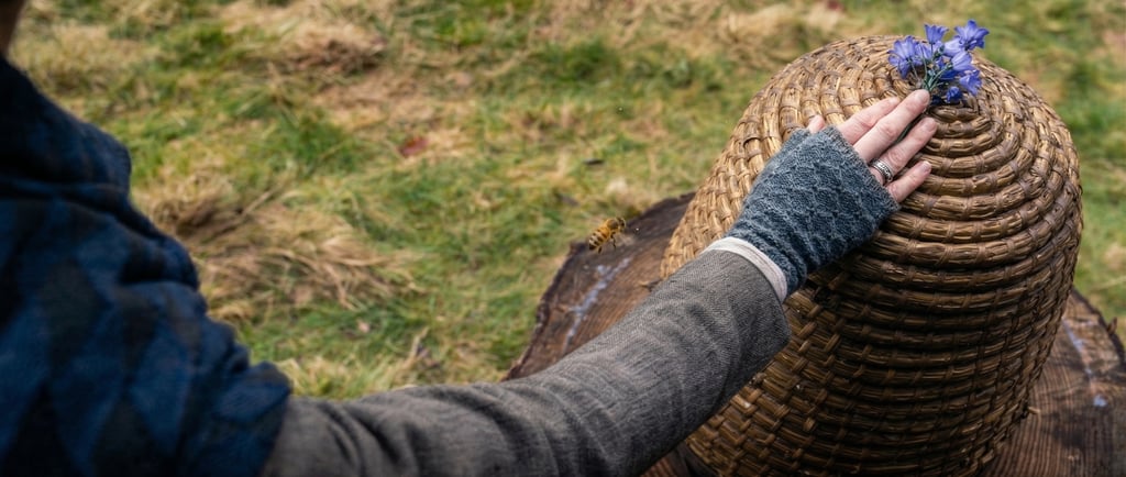 Claire colocando flores sobre una colmena en el ritual de las abejas, tradición que aparece en Outlander