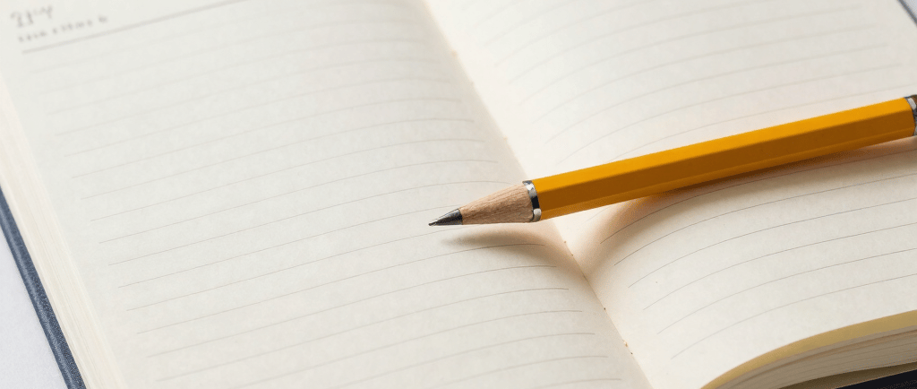 person writing on brown wooden table near white ceramic mug
